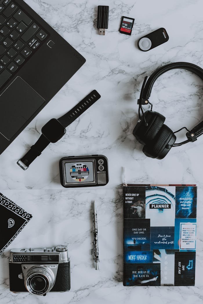 A flat lay composition of digital devices and a vintage camera on a marble surface.