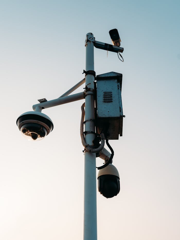 Close-up of a pole with multiple surveillance cameras against a clear sky at dusk.
