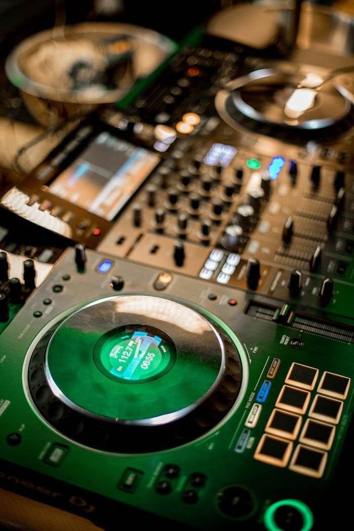 Close-up of a professional DJ mixer console, illuminated in a vibrant setting.